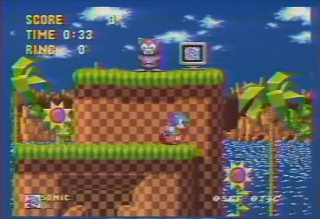 A still from the brief video footage of the early Sonic the Hedgehog, containing a monitor displaying one of the two static frames and the early version of the Ton-ton badnik.