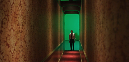 Actor John Hawkes standing at the end of a hallway.