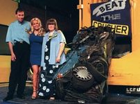 Melinda Messenger with a couple and their crushed Ford Fiesta.